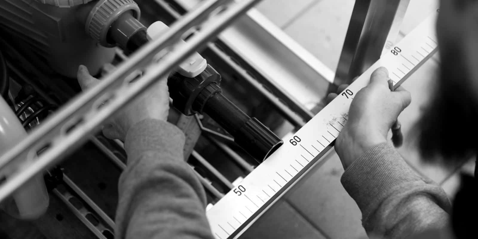 Dettaglio delle mani di un artigiano di Hofer Group mentre misura una parte di un impianto idraulico